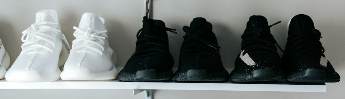 Các đôi giày sneaker đen trắng xếp trên kệ nổi màu trắng