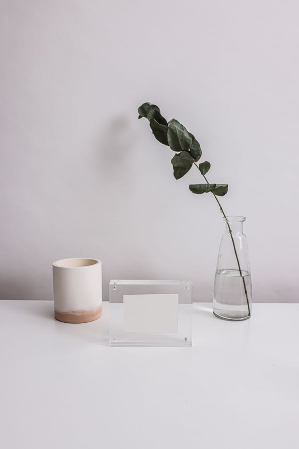 Khung mica trong đặt trên bàn cạnh cốc và lọ thủy tinh