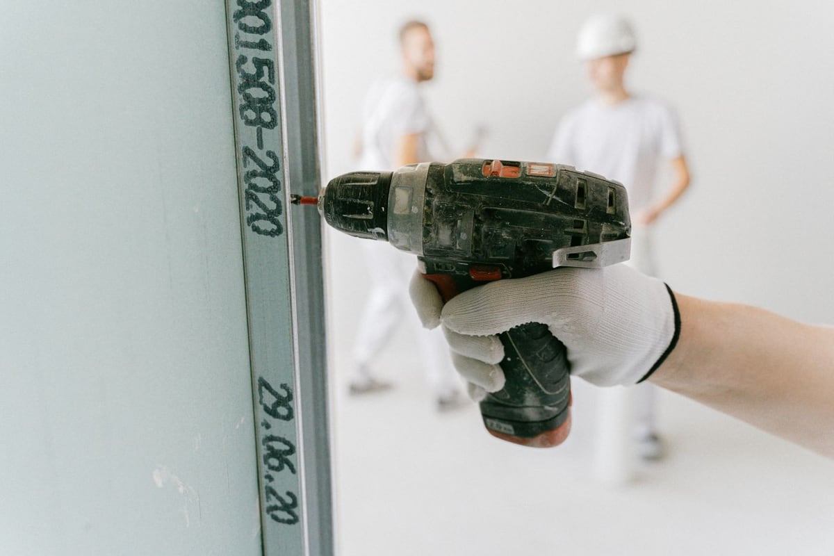 Tay cầm máy khoan đặt lên bức tường