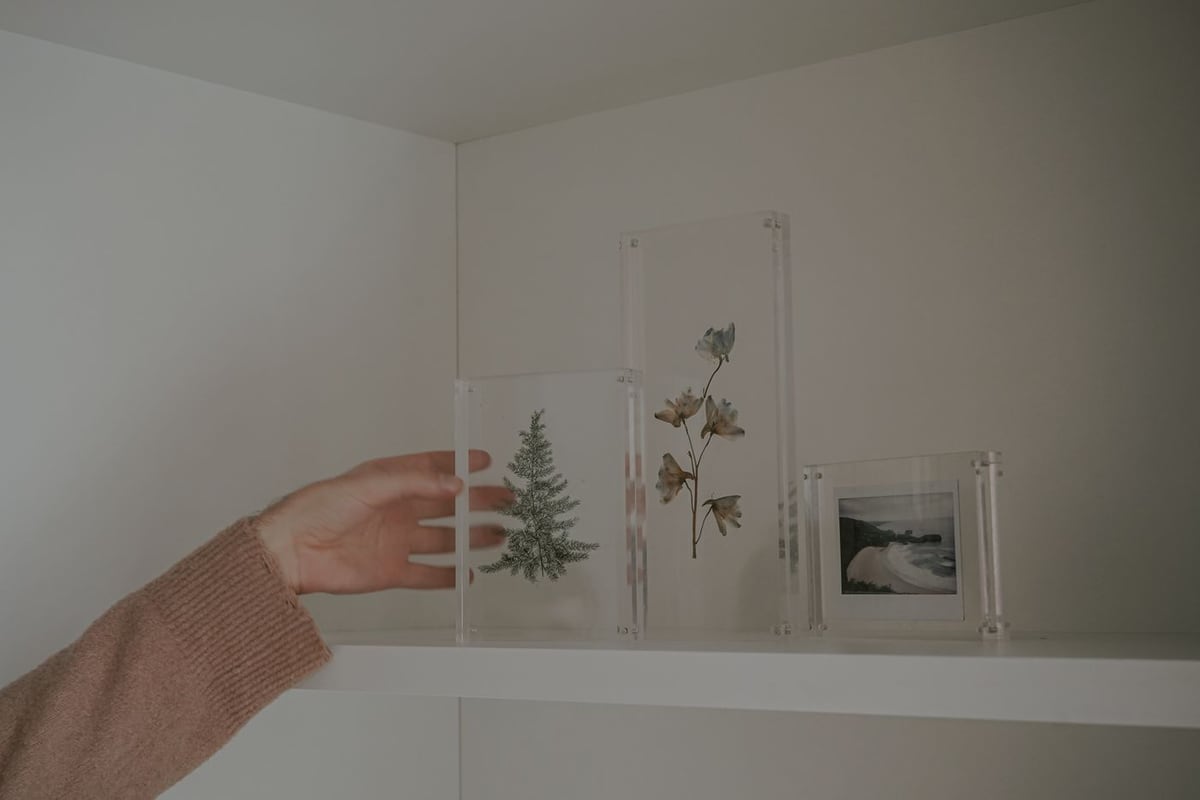 Người đặt tấm mica trong lên kệ trong căn phòng trắng