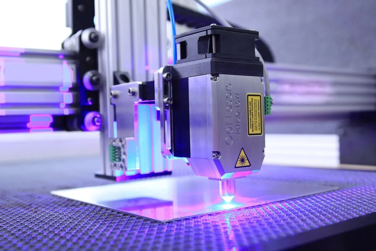 Đầu máy laser đang cắt tấm vật liệu trên bàn máy