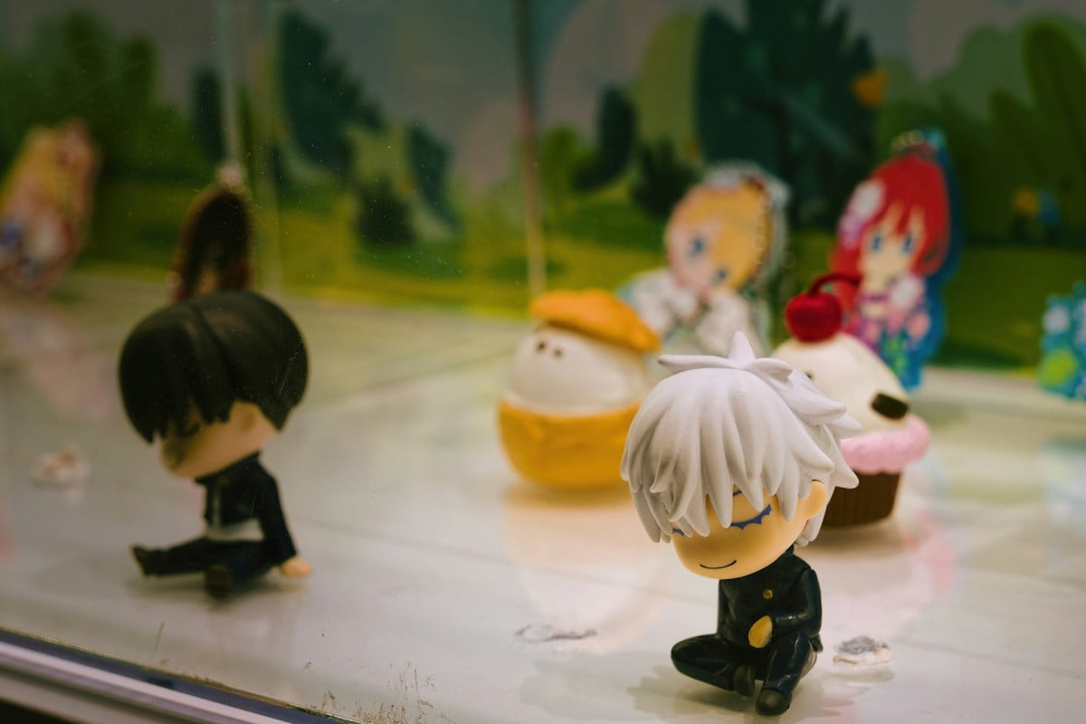 Các nhân vật chibi ngồi trong tủ trưng bày có nền cảnh