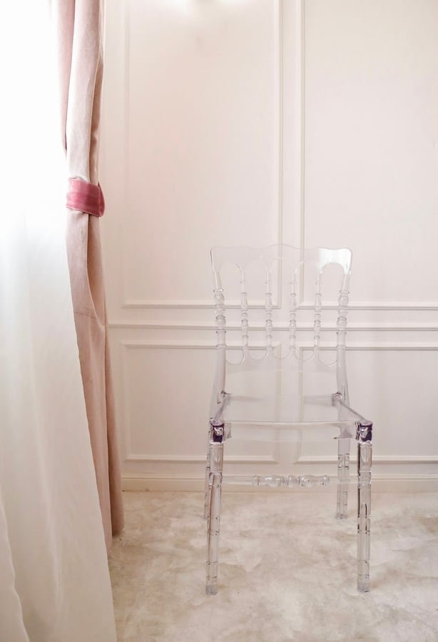 Một chiếc ghế mica trong đặt cạnh rèm cửa sổ
